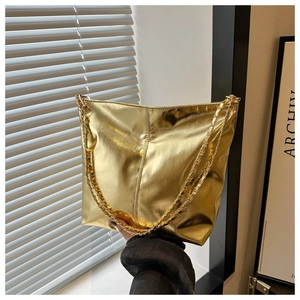 Detail of a metallic gold bucket bag with double chain straps in a lifestyle setting