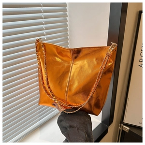Detail of orange metallic PU leather tote bag with elegant golden chain strap