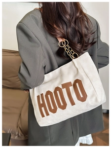 Détail du sac cabas en toile avec patch HOOTO en cuir marron et bandoulière chaîne