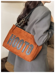 Détail du sac cabas en daim marron avec logo HOOTO et bandoulière en chaîne dorée