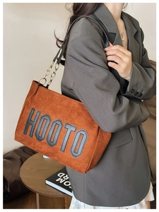 Détail du sac cabas caramel avec patch HOOTO et bandoulière chaîne porté par un mannequin
