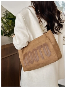 Sac cabas en daim marron avec appliqué HOOTO et bandoulière chaîne porté par un modèle
