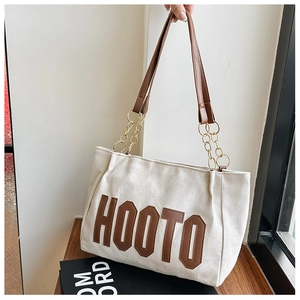 Detail of HOOTO beige tote bag with brown leather letters and gold chain strap