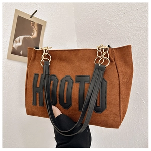 Détail du cabas en daim marron avec écusson noir HOOTO et bandoulière en chaîne dorée