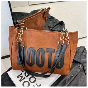 Détail du sac cabas en daim marron avec lettrage MOOTO et bandoulière en chaîne dorée