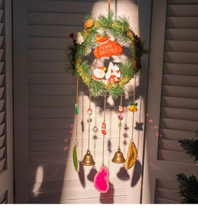 Detail of Christmas wreath wind chime with colorful agate slices and bells on wood background