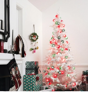 Detail of white flocked Christmas tree with decorative ball lights and festive gift boxes