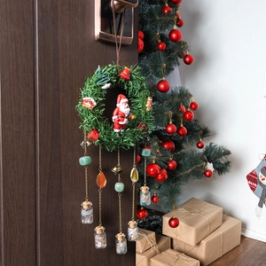 Christmas wreath with Santa figurine, golden bells and stone bottles on a wooden door