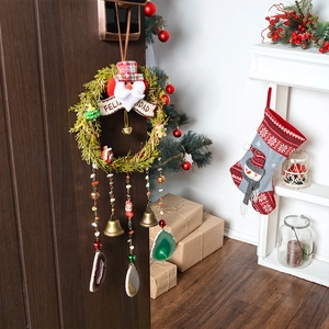 Christmas wreath with Santa, Feliz Navidad banner and natural agate stone hanging on a door