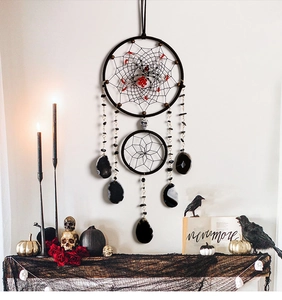 Close-up of gothic Halloween dreamcatcher with spiders and skulls over a cozy fireplace