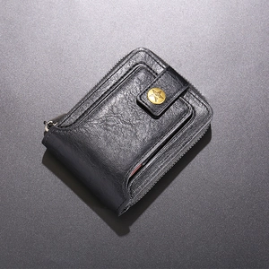 Detail of black pebbled leather wallet with gold star emblem and zip closure