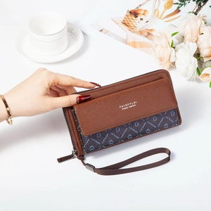 Brown patchwork long wallet with heart print and wristlet strap held by hand