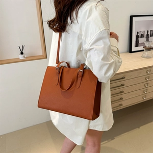 Minimalist caramel Saffiano leather tote bag with silver buckles for daily commute