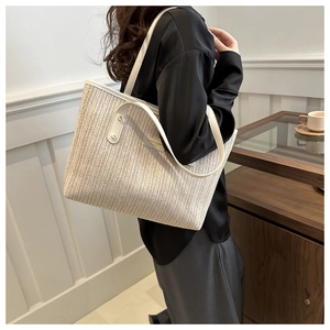Side view of large herringbone woven tote bag with cream leather straps on a model