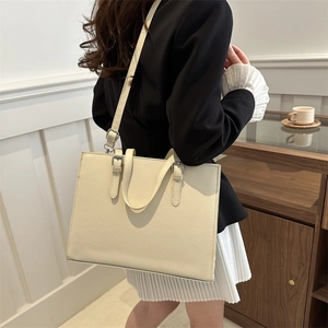 Minimalist beige leather tote bag for women showing single shoulder carry by a model