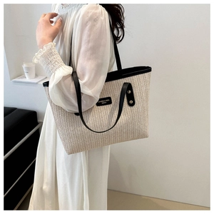 Detail of herringbone weave straw tote bag with black faux leather trim and brand label