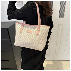 Detailed back view of a beige straw tote bag with pink leather trim worn by a model