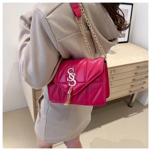 Detailed view of fuchsia quilted shoulder bag with golden tassel on the model