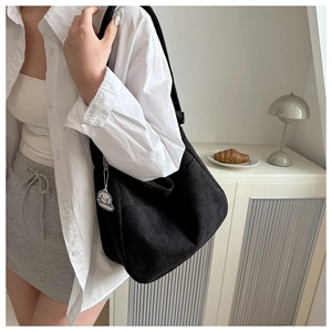 Detail shot of black corduroy tote bag with cute dog pendant accessory on shoulder