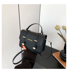 Close-up of black leather crossbody bag featuring gold hardware and logo detail