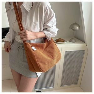 Detailed texture of brown corduroy crossbody bag with a cute white cartoon animal charm