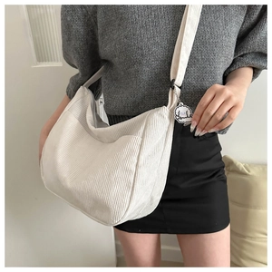 Detail of off-white corduroy crossbody crescent bag with adjustable strap and cute dog pendant