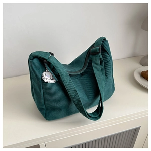Detail of dark green corduroy tote bag with adjustable strap and cute dog plush charm