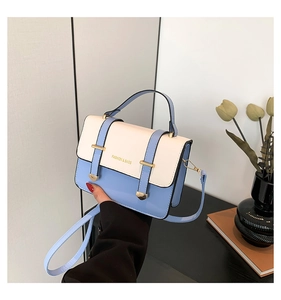 Detail of blue and white contrast leather crossbody bag with gold buckle and fashion text