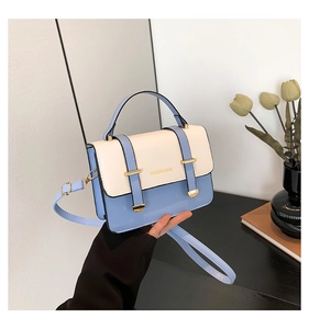 Detail of blue and cream PU leather crossbody bag with gold hardware and logo text