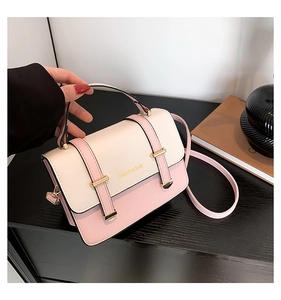 Detail of pink and white crossbody bag with gold square lock and logo held by hand