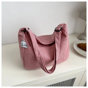 Detail of pink corduroy tote bag with adjustable strap and cute white puppy charm