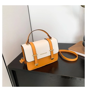 Detail of a two-tone square crossbody bag featuring yellow accents and gold metal buckles