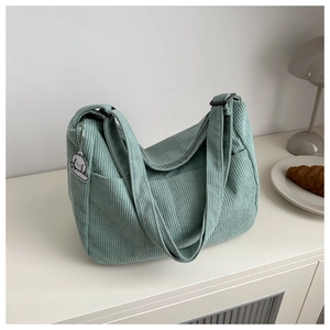 Close-up of light green corduroy tote bag with zipper and cute puppy pendant accessory