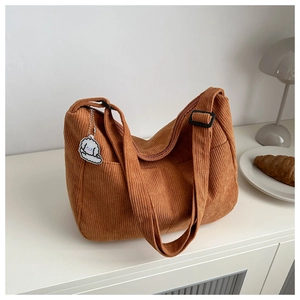 Detail of brown corduroy tote bag with texture, adjustable buckle and dog charm