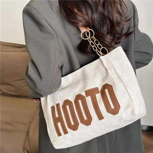 Minimalist white tote bag with HOOTO leather patch and gold chain strap shown on model