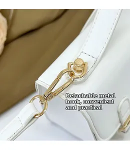 Close-up of detachable gold metal hook on white faux leather shoulder bag