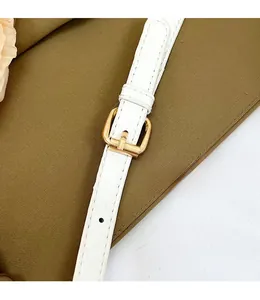 Detail of adjustable white leather strap with gold buckle and precise stitching