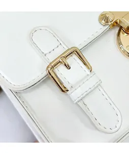 Detail view of white leather handbag with elegant gold metal buckle and precision stitching