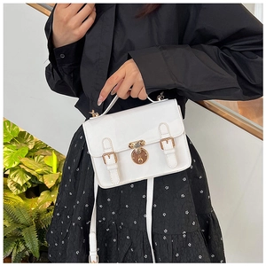 Macro shot of white patent leather messenger bag with gold hardware and metal lock