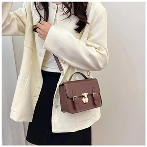 Detail of retro brown crossbody bag with gold hardware and removable shoulder strap on model