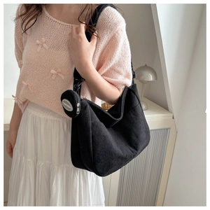 Gros plan détaillé du sac bandoulière en velours côtelé noir avec texture à côtes et pochette
