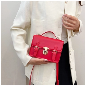 Detail of red synthetic leather handbag with gold metal buckles and vintage round lock