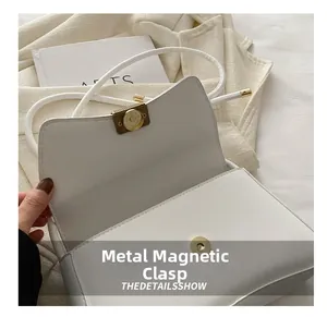 Close-up of white leather shoulder bag featuring a premium gold metal magnetic clasp