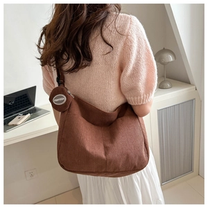 Detailed texture of brown corduroy shoulder bag with small circular coin purse accessory