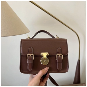 Close-up of retro dark brown PU messenger bag with golden buckle and strap details