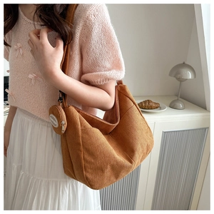 Detail of brown corduroy tote bag with round zipper pouch on a stylish model