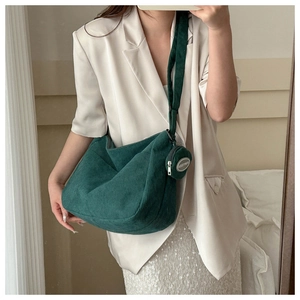 Dark green corduroy tote bag with small coin purse shown on a white blazer outfit
