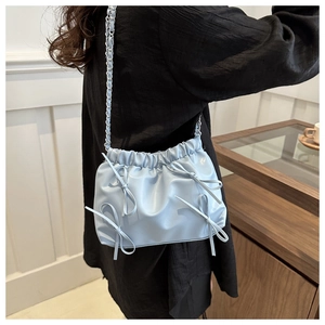 Détail du sac seau bleu clair avec nœuds faits main et bandoulière chaîne argentée