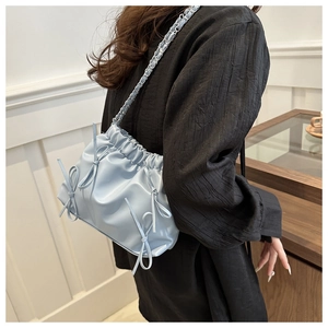 Détail d'un sac à main bleu clair avec nœuds et bandoulière chaîne en décor intérieur