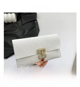 Detailed view of white envelope clutch featuring crocodile embossing and gold geometric lock